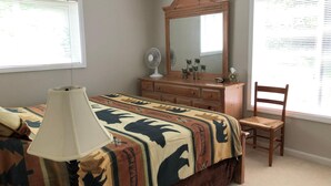 A bedroom with a bed, a dresser, a chair, a lamp, a mirror, and windows with blinds. - Sugar Ski & Country Club Unit 811 Gold (Banner Elk)