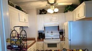 A compact kitchen with white cabinets, a white refrigerator, a stove, and a wine rack. - Sugar Ski & Country Club Unit 811 Gold (Banner Elk)