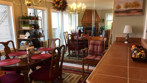 A dining area with a wooden table and chairs, a chandelier, and a fruit bowl on the counter. - Sugar Ski & Country Club Unit 811 Gold (Banner Elk)