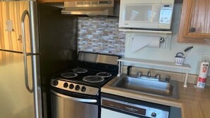 A compact kitchen with a stainless steel refrigerator, a built-in stove with four burners, a microwave, and a dishwasher. - Sugar Ski & Country Club Unit 125 Silver (Banner Elk)