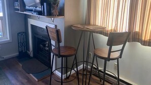 A living room with a fireplace, two chairs, a small table, and a television on a shelf. - Sugar Ski & Country Club Unit 125 Silver (Banner Elk)