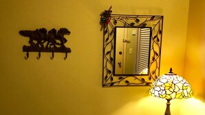 A wall with a decorative horse sculpture, a mirror with a leaf pattern, and a table with a plate and a lamp. - 10-503 (Banner Elk)