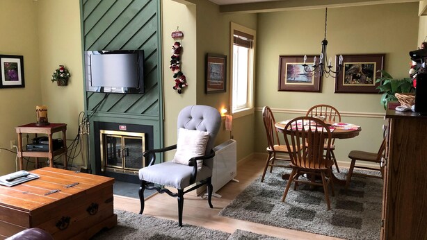 A cozy living room with a fireplace, a television, a dining table with chairs, and a comfortable armchair. - 10-503 (Banner Elk)
