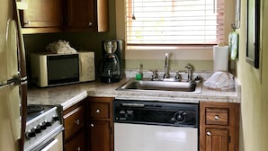 A kitchen with wooden cabinets, a microwave, a stove, a sink, and a window with blinds. - 10-503 (Banner Elk)