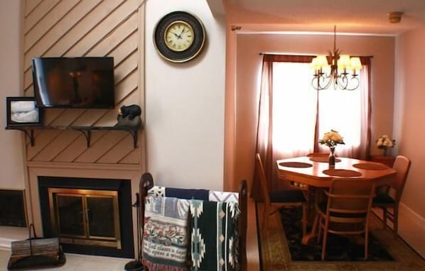 Cozy dining area with a round table, comfortable chairs, and a fireplace.