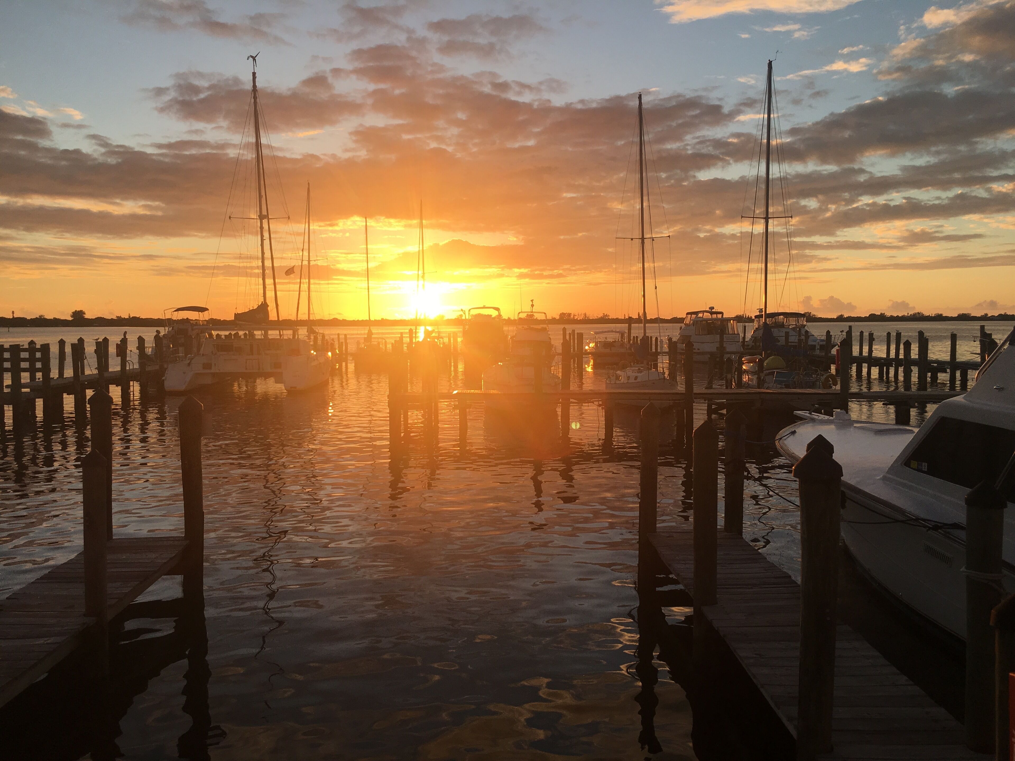 A marina at sunset with boats docked and a clear sky.