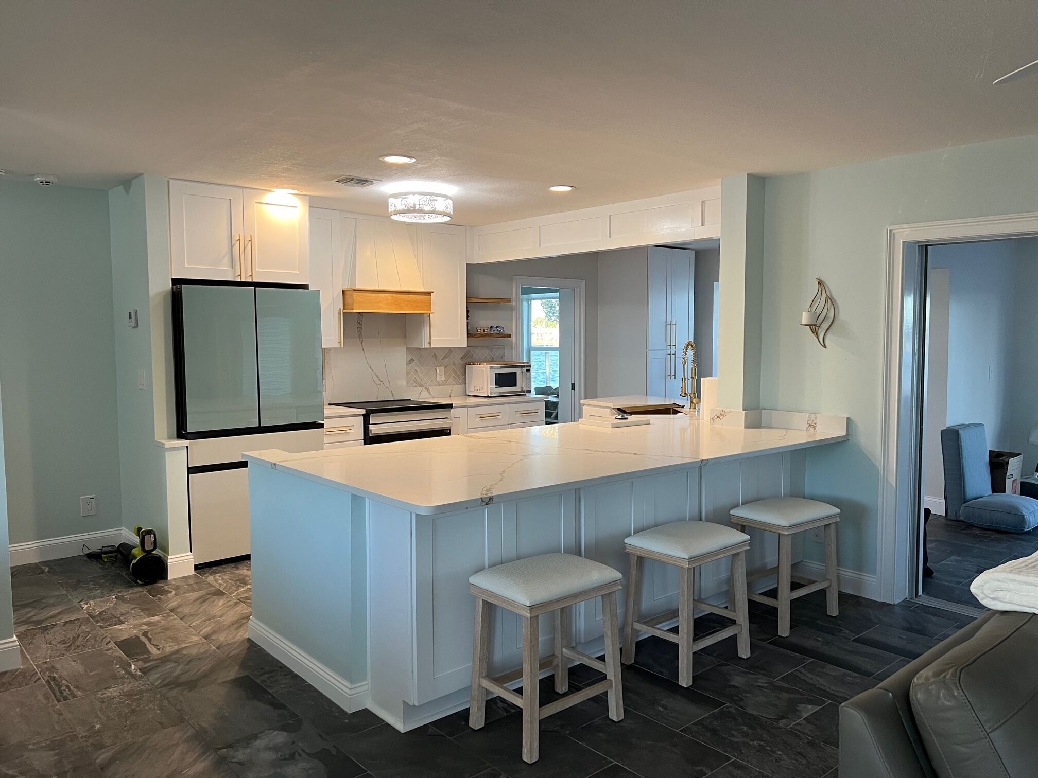 Cozinha moderna com uma ilha grande, banquetas e vista para a sala de jantar.