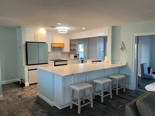 A modern kitchen with a large island, bar stools, and a view to the dining area.