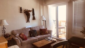 Ein Wohnzimmer mit einer Couch, einem Couchtisch, einer Lampe und einer Schiebetür zu einem Außenbereich.