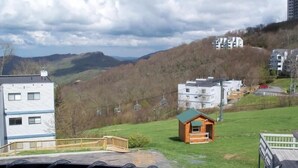 Une vue d’une colline avec une petite cabane et un bâtiment doté d’un toit végétalisé.