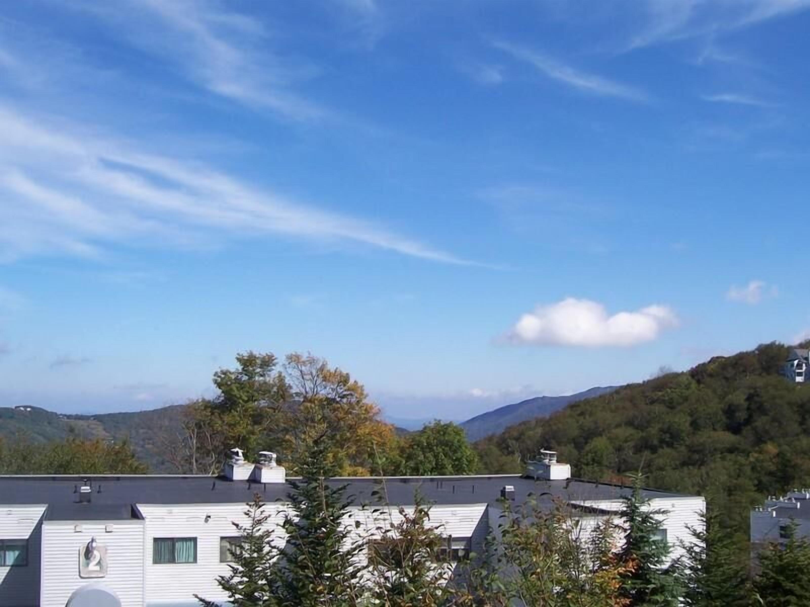 A residential area with white houses, a clear blue sky, and a mountainous backdrop.
