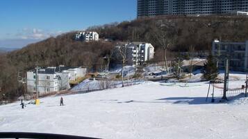 A snowy ski slope with buildings in the background.