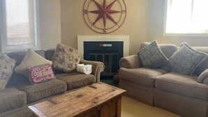 Ein Wohnzimmer mit zwei Sofas, einem Couchtisch und einem Kamin.