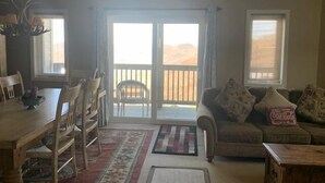 Ein Wohnzimmer mit Essbereich, einer Couch mit Kissen, einem Couchtisch und Blick auf die Wüste durch die Schiebetüren.