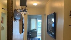 A hallway with a patterned rug, a wall-mounted light fixture, and a framed picture. - Sugar Ski & Country Club Unit 433 Gold (Banner Elk)