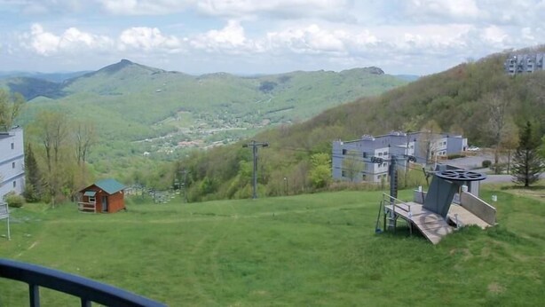 A view of a green valley with a small cabin and a large building with a unique roof structure. - Sugar Ski & Country Club Unit 433 Gold (Banner Elk)