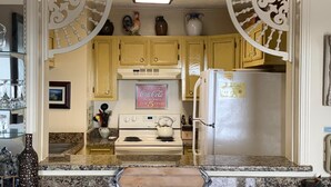 A kitchen with yellow cabinets, a white stove, a refrigerator, and a Coca-Cola sign. - Sugar Ski & Country Club Unit 433 Gold (Banner Elk)
