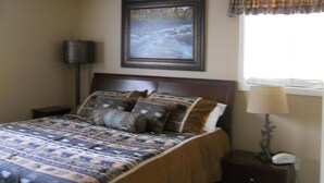 A bedroom with a bed, a ceiling fan, a framed picture, a lamp, and a window with a curtain. - Sugar Ski & Country Club Unit 511 Gold (Banner Elk)