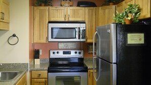 A kitchen with wooden cabinets, a stainless steel refrigerator, a microwave, and an oven. - Sugar Ski & Country Club Unit 511 Gold (Banner Elk)