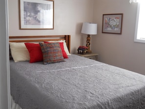 A neatly made bed with a patterned bedspread, a wooden headboard, and a bedside table with a lamp and a small decorative item. - Sugar Ski & Country Club Unit 531 Silver (Banner Elk)