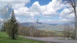 A view of a road with a bench in the foreground, a row of trees, and a distant landscape with hills and a clear sky. - Sugar Ski & Country Club Unit 615 Platinum (Banner Elk)