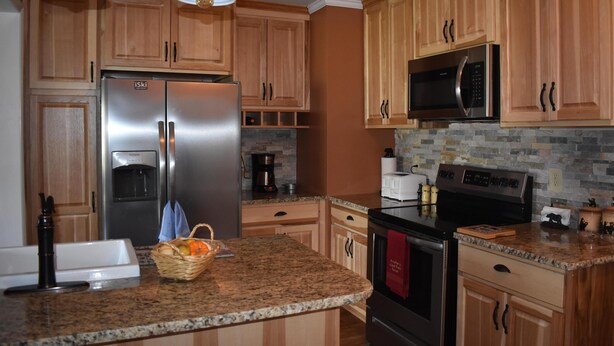 A kitchen with wooden cabinets, stainless steel appliances, granite countertops, and pendant lighting. - Sugar Ski & Country Club Unit 615 Platinum (Banner Elk)
