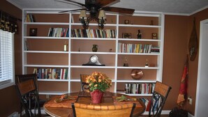 A dining area with a wooden table, four chairs, and a bookshelf filled with books and decorative items. - Sugar Ski & Country Club Unit 615 Platinum (Banner Elk)
