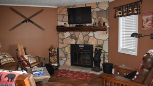 A cozy living room with a stone fireplace, a mounted TV, and a bear statue. - Sugar Ski & Country Club Unit 615 Platinum (Banner Elk)