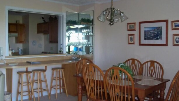 A dining area with a wooden table and chairs, a kitchen area with a bar, and a mirror reflecting the kitchen. - Sugar Ski & Country Club Unit 822 Silver (Banner Elk)