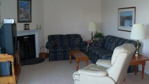 A living room with a fireplace, a sofa, a chair, and two lamps. - Sugar Ski & Country Club Unit 822 Silver (Banner Elk)
