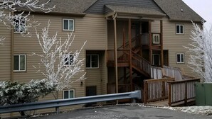 A multi-story building with a central staircase, balconies, and a gated entrance. - Sugar Ski & Country Club Unit 11-403 Gold (Banner Elk)