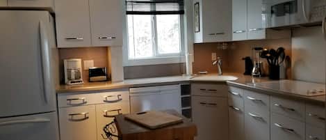 A modern kitchen with white cabinets, a built-in microwave, and a coffee maker.
