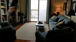 A living room with a sofa, armchairs, a coffee table, a TV, a fireplace, and a balcony with a view. - Sugar Ski & Country Club Unit 11-403 Gold (Banner Elk)