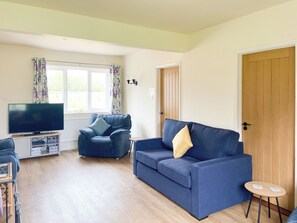 A living room with a TV, two sofas, a small table, and a door. - Old Alton Hall Farmhouse (Holbrook, near Ipswich)