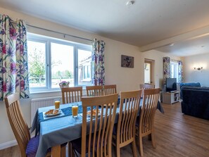A dining area with a table set for breakfast, wooden chairs, and a view of the outdoors through large windows. - Old Alton Hall Farmhouse (Holbrook, near Ipswich)