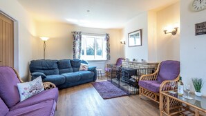 A cozy living room with a blue sofa, purple armchairs, a small table with glasses, and a window with curtains. - Old Alton Hall Farmhouse (Holbrook, near Ipswich)