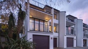 A modern multi-story residential building with a flat roof, large windows, and balconies.
