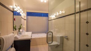 A modern bathroom with a bathtub, toilet, and shower area.