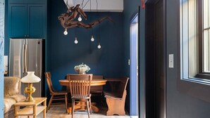 Een moderne keuken met donkerblauwe kastjes, een houten eettafel en een bijzondere kroonluchter.