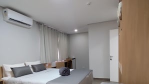 Ein Hotelzimmer mit einem großen Bett, einem kleineren Bett, einem Schreibtisch und einem Kleiderschrank.