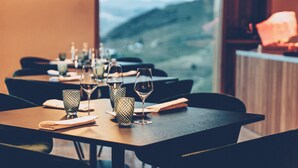 Mesa con copas de vino y servilleta, con vista a un paisaje montañoso a través de una ventana.