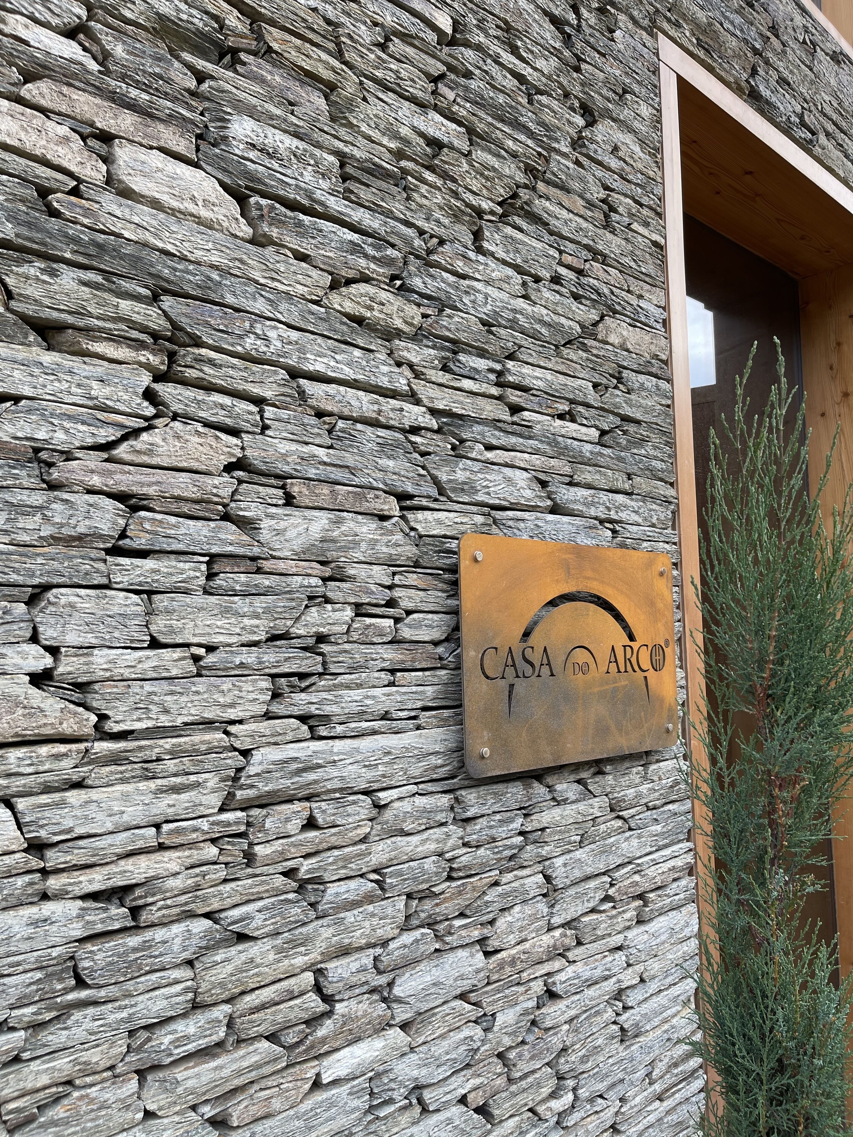 Un muro de piedra con un cartel que dice "CASA DO ARCO".