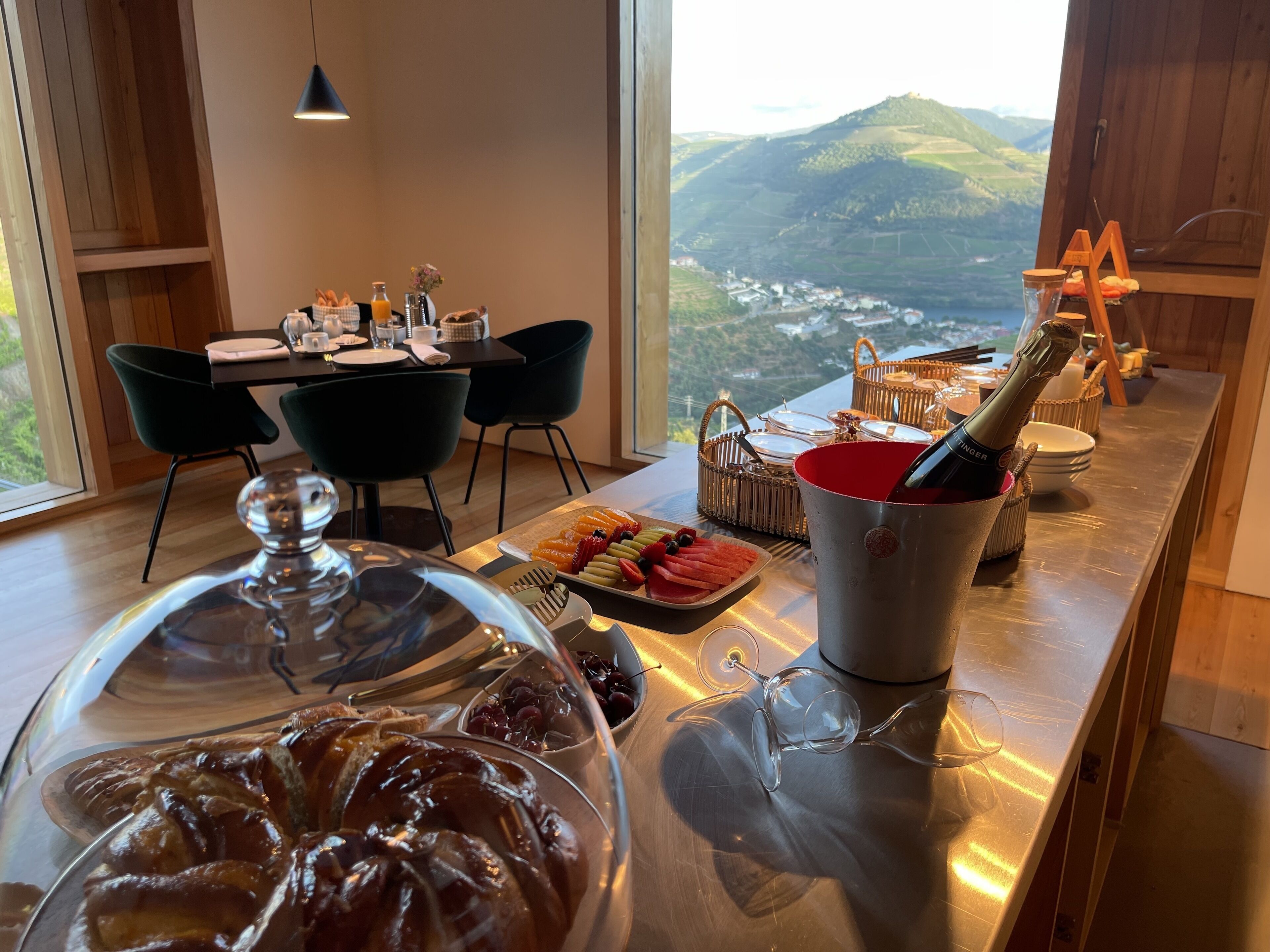 Monipuolinen aamiaisbuffet, jossa on tarjolla erilaisia leivonnaisia, hedelmiä ja pullo samppanjaa.