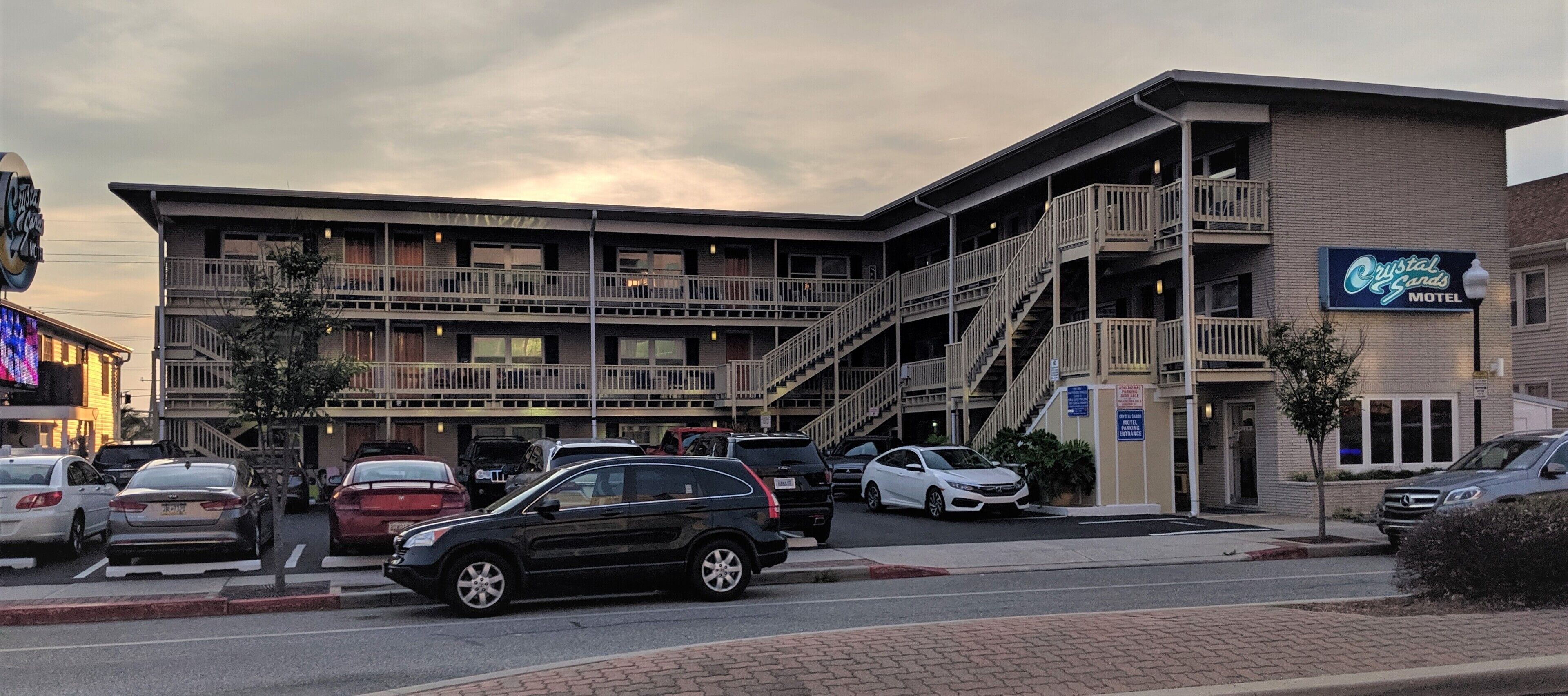 Un motel composé d’un bâtiment à plusieurs étages, d’un parking et d’un escalier menant aux étages supérieurs.
