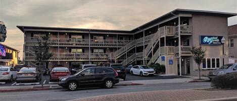 Un motel composé d’un bâtiment à plusieurs étages, d’un parking et d’un escalier menant aux étages supérieurs.