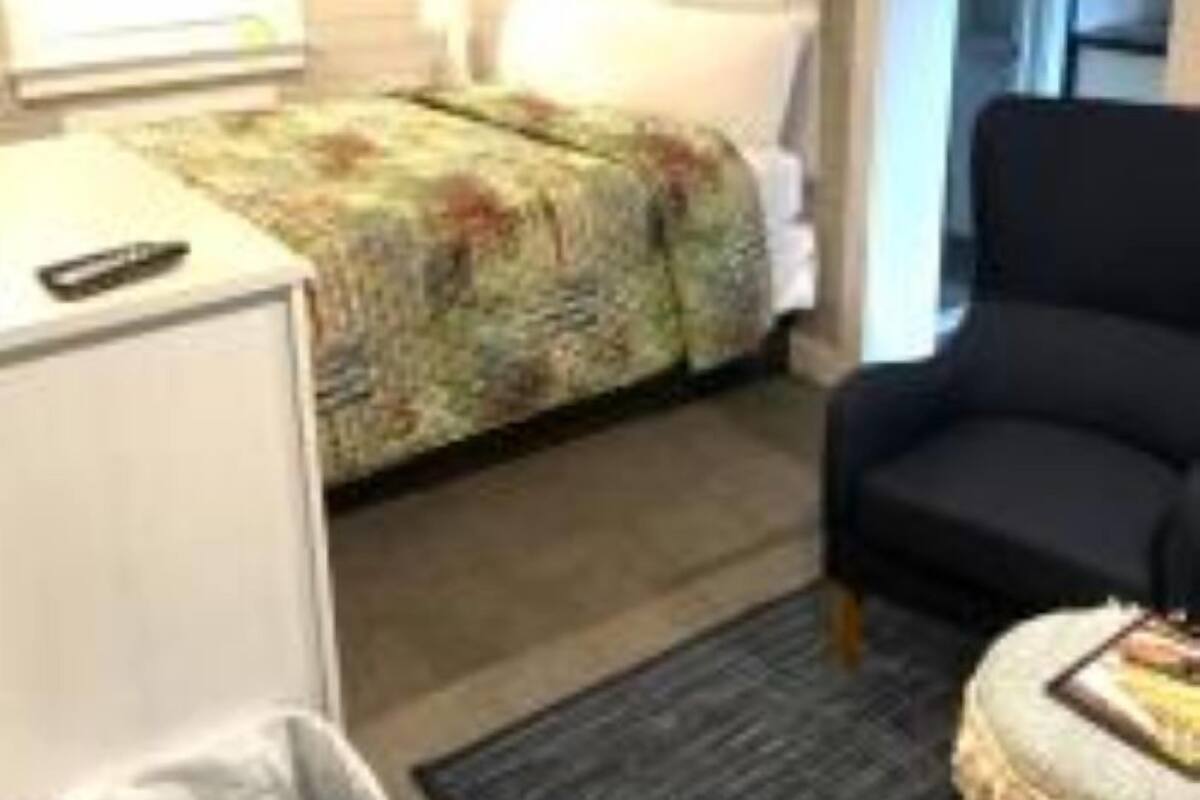 A hotel room with a bed, a chair, a small table, and a window.