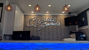 A reception area with a 'Crystal Gardens' sign, a laptop, and a black HP device on a counter. - Crystal Sands Motel (Ocean City)