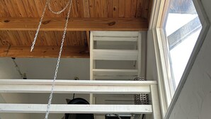 Ein Loft-Zimmer mit freiliegenden Holzbalken, einem Oberlicht und einem schwarzen Abluftventilator.