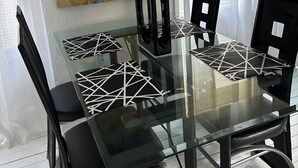 Ein moderner Essbereich mit einem Glastisch, schwarzen Stühlen und einem farbenfrohen, abstrakten Gemälde an der Wand.