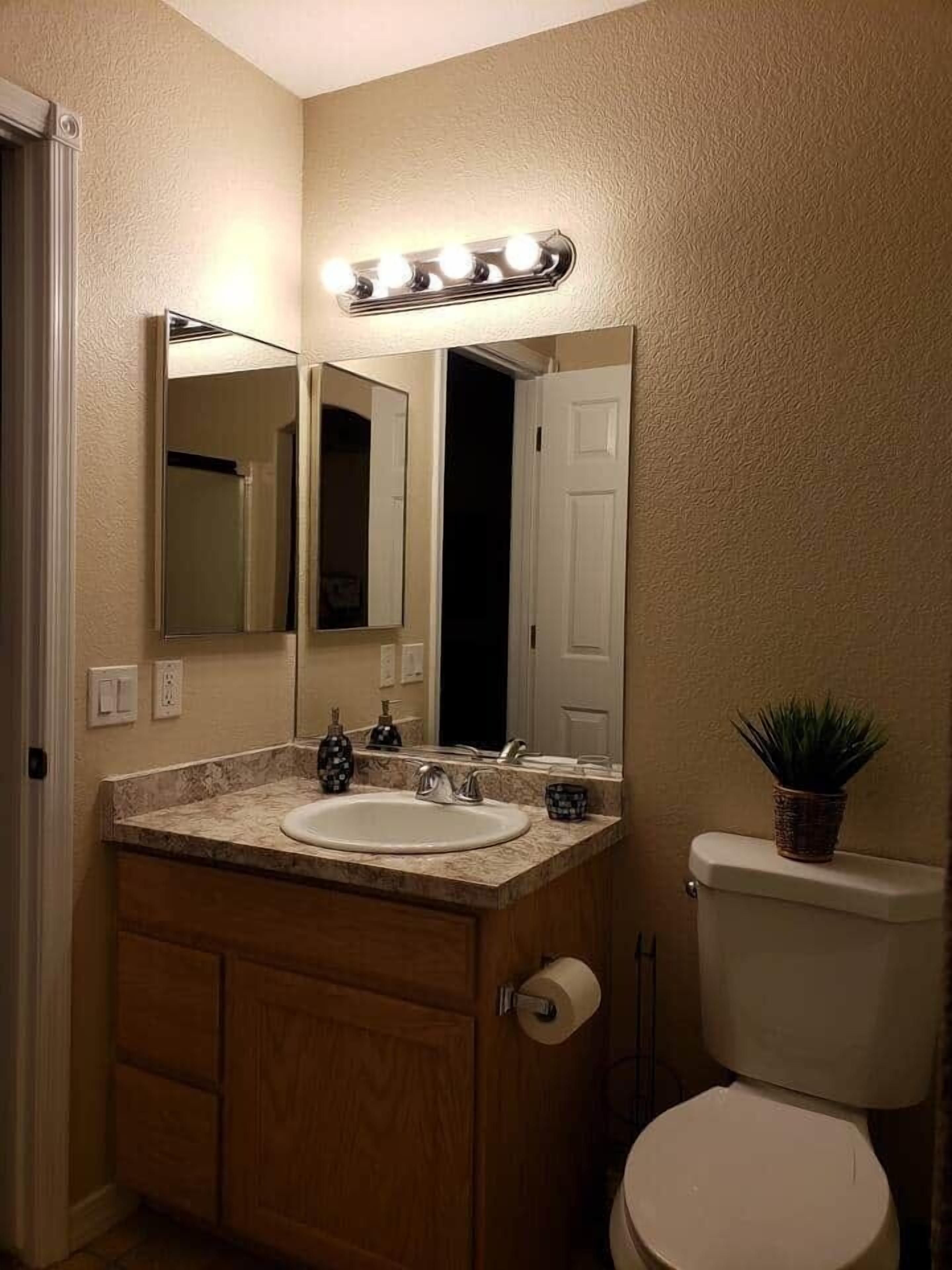 Ein Badezimmer mit Waschtisch, Spüle, Spiegel und Toilette.